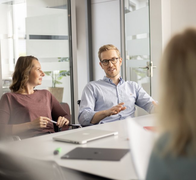 Drei Mitarbeitende im Gespräch am Besprechungstisch